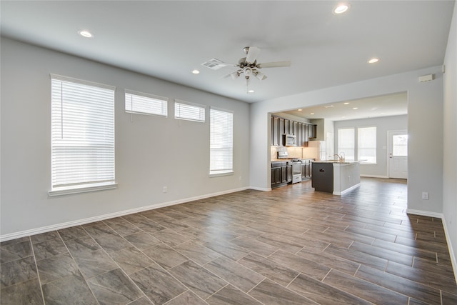 unfurnished living room with ceiling fan and sink