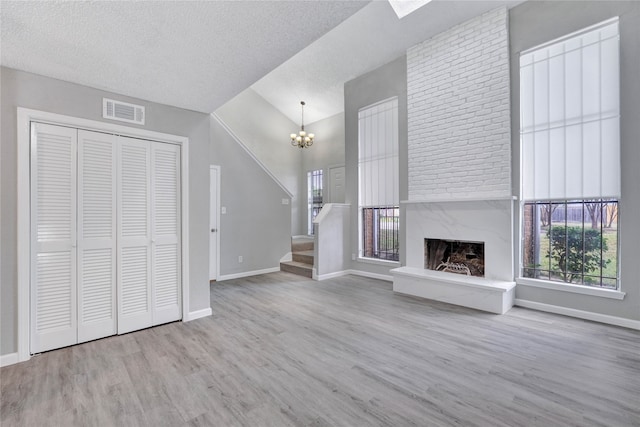 unfurnished living room featuring a textured ceiling, a fireplace, light hardwood / wood-style floors, and a healthy amount of sunlight