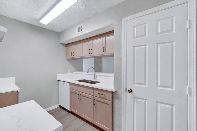 kitchen featuring light wood-type flooring, dishwasher, sink, light brown cabinetry, and a textured ceiling