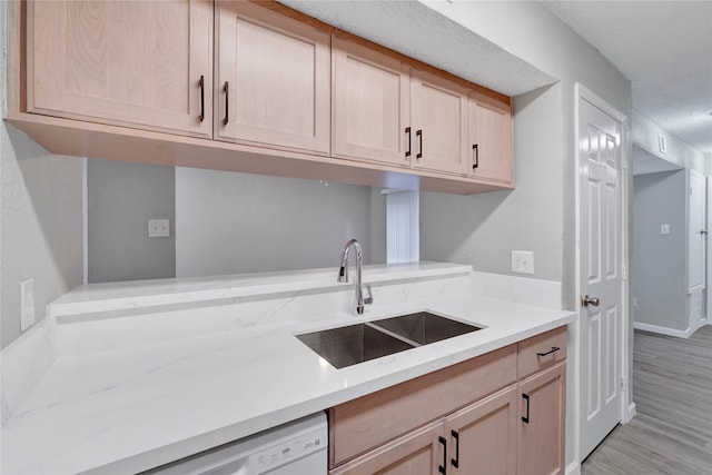 kitchen with dishwasher, light brown cabinetry, light hardwood / wood-style floors, and sink