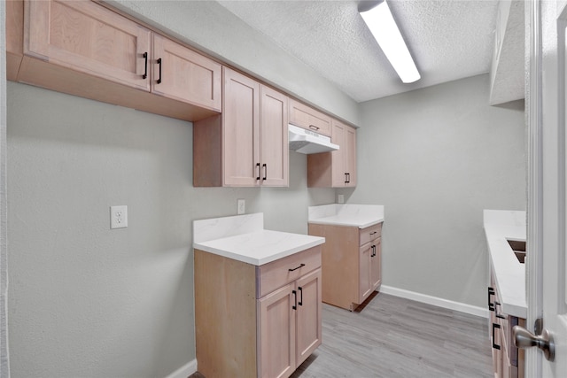 kitchen featuring light hardwood / wood-style floors, light brown cabinets, and a textured ceiling