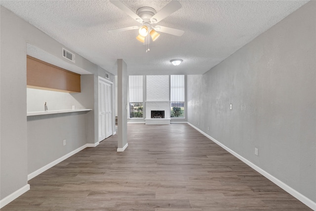 unfurnished living room featuring hardwood / wood-style flooring, ceiling fan, and a textured ceiling