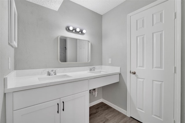 bathroom with hardwood / wood-style floors, vanity, and a textured ceiling