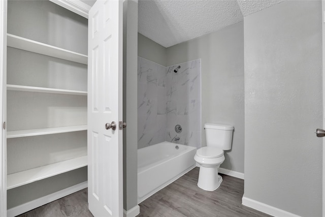 bathroom with tiled shower / bath, hardwood / wood-style flooring, a textured ceiling, and toilet