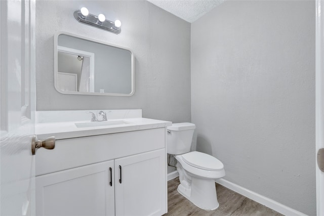 bathroom featuring vanity, toilet, wood-type flooring, and a textured ceiling