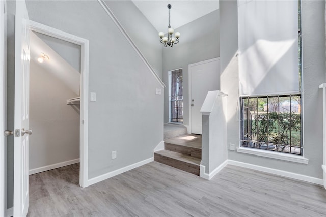 foyer entrance featuring a notable chandelier, light wood-type flooring, and high vaulted ceiling