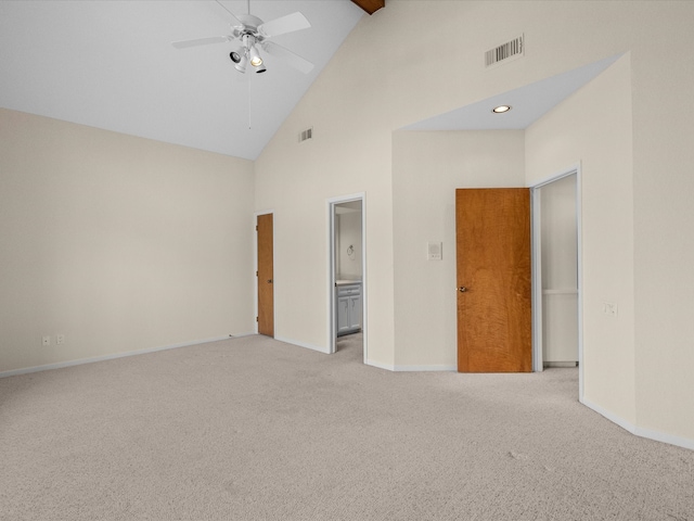 unfurnished bedroom with high vaulted ceiling, ceiling fan, connected bathroom, and light colored carpet