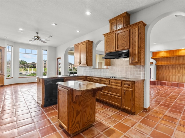 kitchen with kitchen peninsula, backsplash, a center island, black appliances, and a breakfast bar