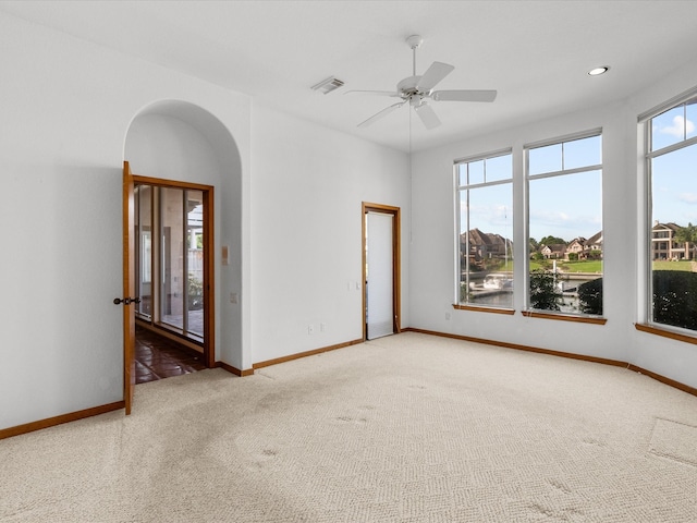 carpeted empty room with a water view and ceiling fan