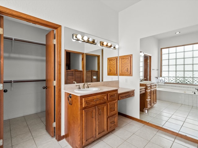 bathroom with tiled tub, vanity, and tile patterned floors