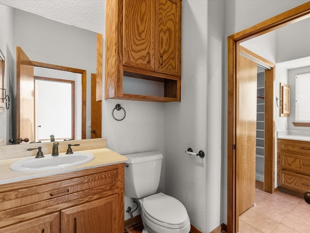 bathroom featuring vanity, toilet, a textured ceiling, and tile patterned floors