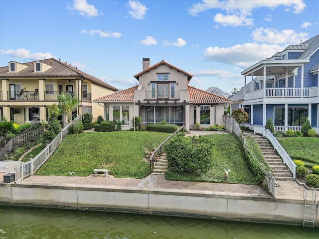 back of property featuring a water view, cooling unit, a balcony, and a lawn