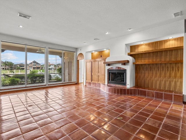 unfurnished living room with wood walls, dark tile patterned floors, and a textured ceiling