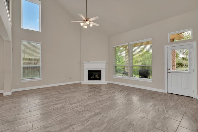 unfurnished living room with ceiling fan and high vaulted ceiling