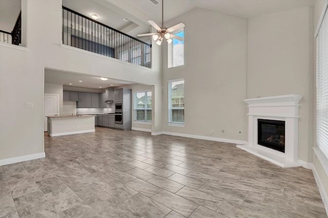 unfurnished living room with high vaulted ceiling, ceiling fan, and beamed ceiling