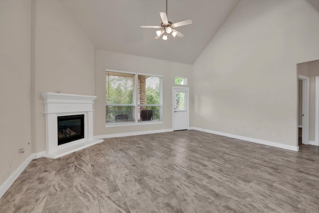 unfurnished living room with ceiling fan and high vaulted ceiling