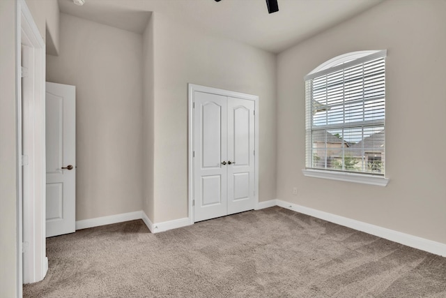 unfurnished bedroom with light carpet, ceiling fan, and a closet