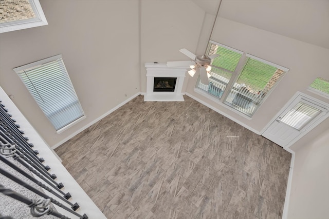 unfurnished living room featuring plenty of natural light, ceiling fan, and high vaulted ceiling