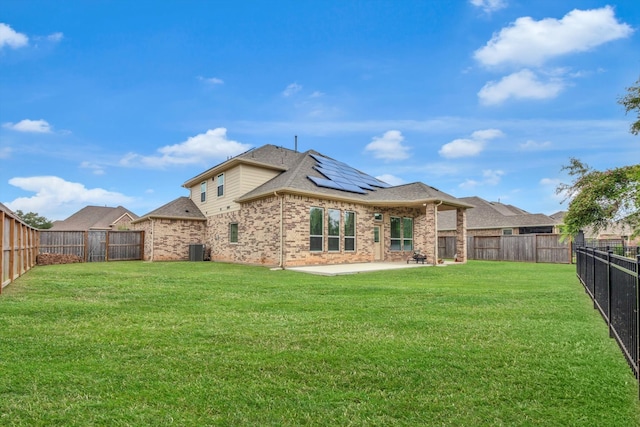 rear view of house with a lawn, solar panels, a patio, and central AC unit