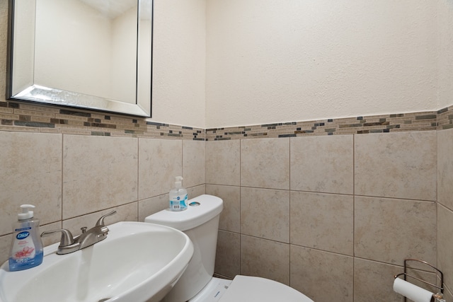 bathroom featuring tile walls, sink, and toilet