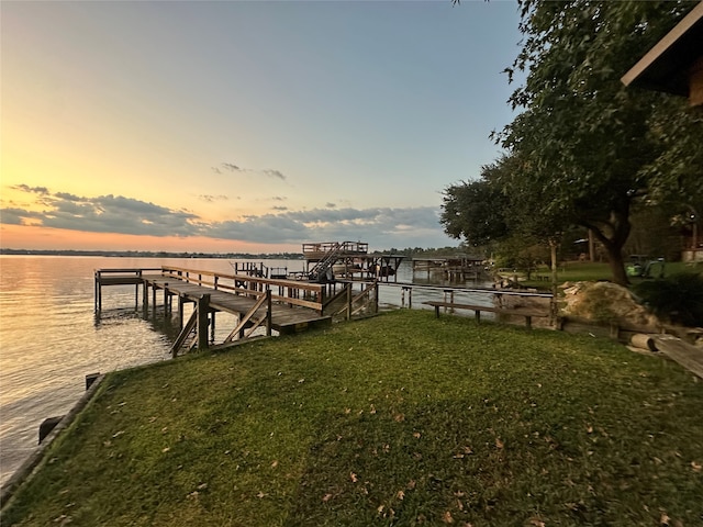 view of dock featuring a water view and a lawn