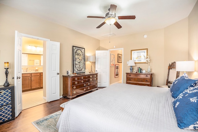 bedroom featuring ceiling fan, light hardwood / wood-style flooring, and connected bathroom