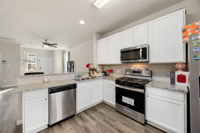 kitchen featuring kitchen peninsula, stainless steel appliances, and white cabinets