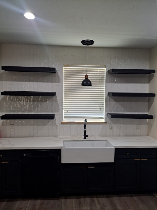 kitchen with dishwasher, light stone counters, dark wood-type flooring, and sink