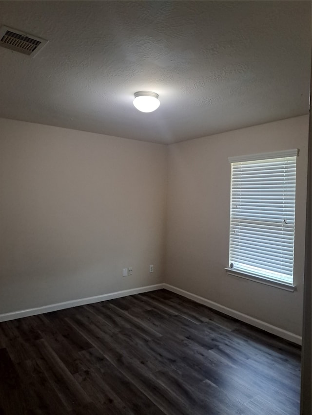 spare room with a textured ceiling and dark hardwood / wood-style flooring