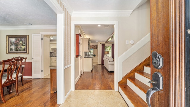 foyer featuring a textured ceiling, light hardwood / wood-style floors, and crown molding