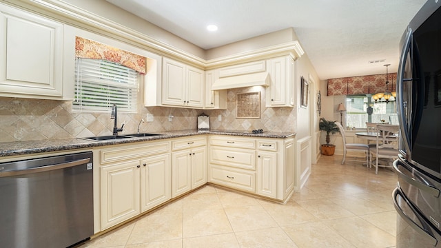 kitchen featuring sink, cream cabinetry, backsplash, black refrigerator, and stainless steel dishwasher