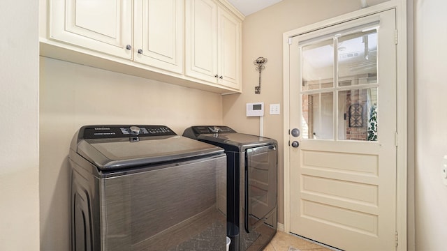 laundry area with light tile patterned floors, cabinets, and washer and dryer