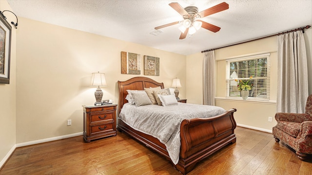 bedroom with ceiling fan, hardwood / wood-style floors, and a textured ceiling