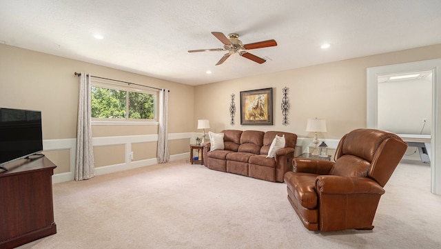 living room featuring ceiling fan, light colored carpet, and a textured ceiling