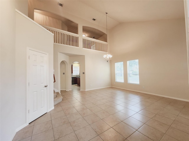 tiled spare room with sink, high vaulted ceiling, and a chandelier