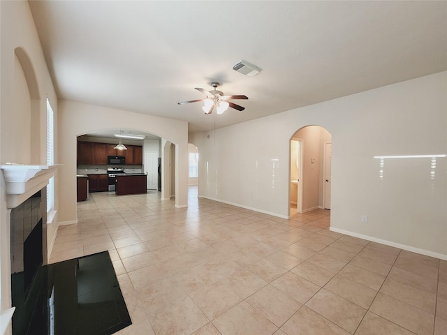 unfurnished living room with ceiling fan, light tile patterned floors, and a tile fireplace