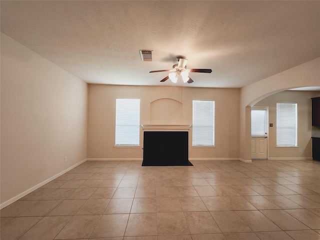 unfurnished living room featuring a wealth of natural light, ceiling fan, and light tile patterned floors