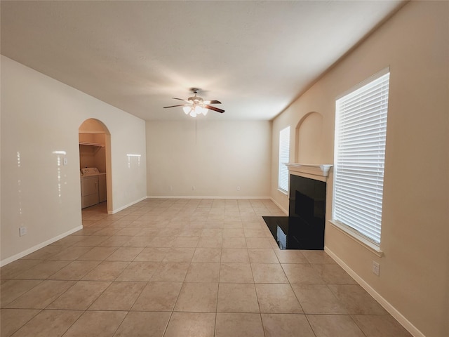 unfurnished living room with ceiling fan, light tile patterned floors, and washing machine and clothes dryer