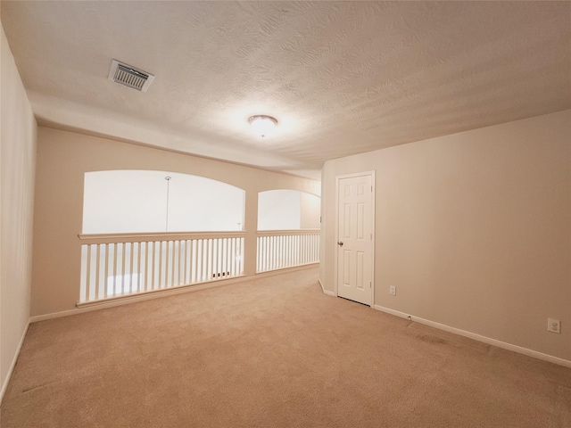 carpeted empty room with a textured ceiling