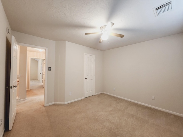 unfurnished bedroom featuring ceiling fan, light colored carpet, and a textured ceiling