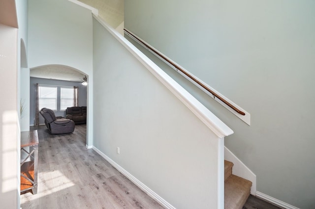 stairs with wood-type flooring and ceiling fan