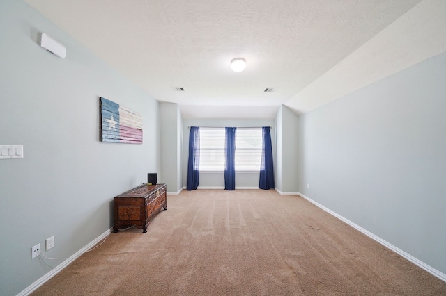 spare room with lofted ceiling, a textured ceiling, and light colored carpet