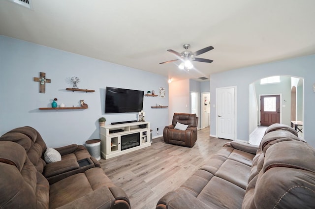 living room with a fireplace, ceiling fan, and light hardwood / wood-style flooring