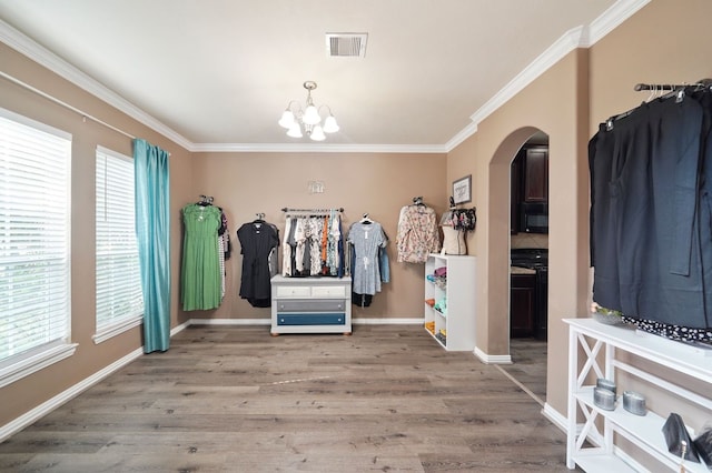 entryway featuring wood-type flooring, ornamental molding, and a notable chandelier