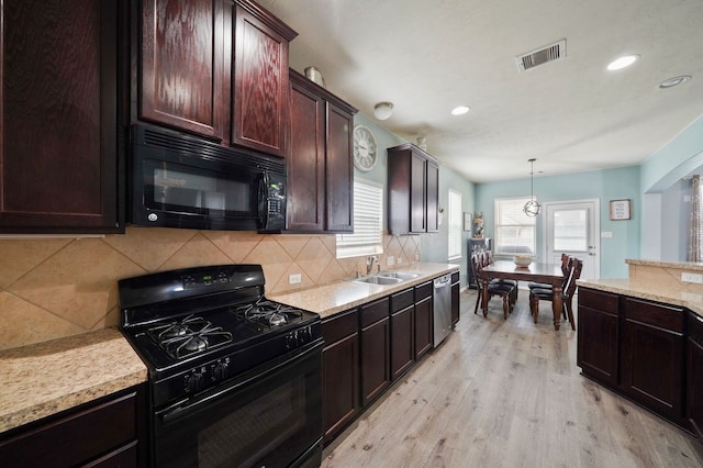 kitchen featuring decorative backsplash, light hardwood / wood-style floors, black appliances, decorative light fixtures, and sink