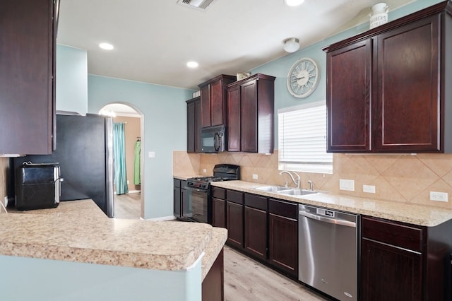 kitchen with kitchen peninsula, sink, tasteful backsplash, light hardwood / wood-style flooring, and black appliances