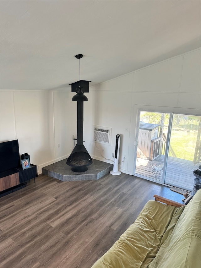 unfurnished living room featuring lofted ceiling, hardwood / wood-style flooring, a wood stove, and a wall mounted AC