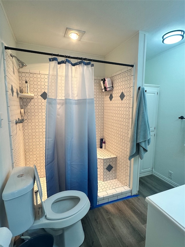 bathroom with toilet, crown molding, wood-type flooring, and curtained shower