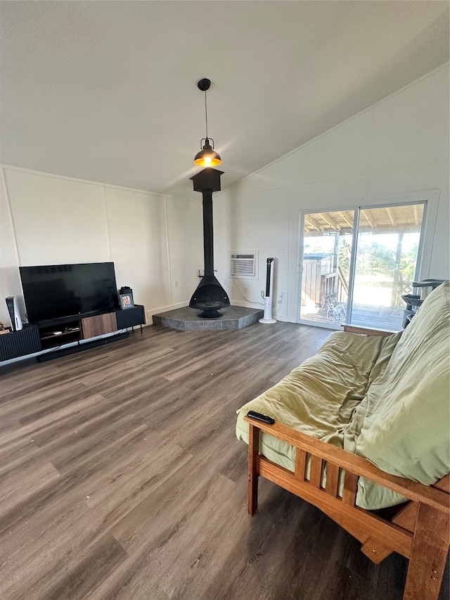 living room with a wood stove, hardwood / wood-style flooring, an AC wall unit, and vaulted ceiling