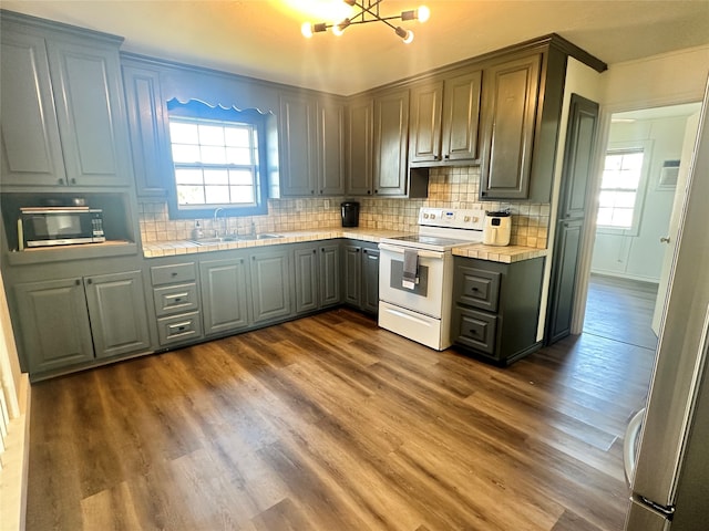 kitchen with gray cabinetry, sink, electric range, dark wood-type flooring, and decorative backsplash